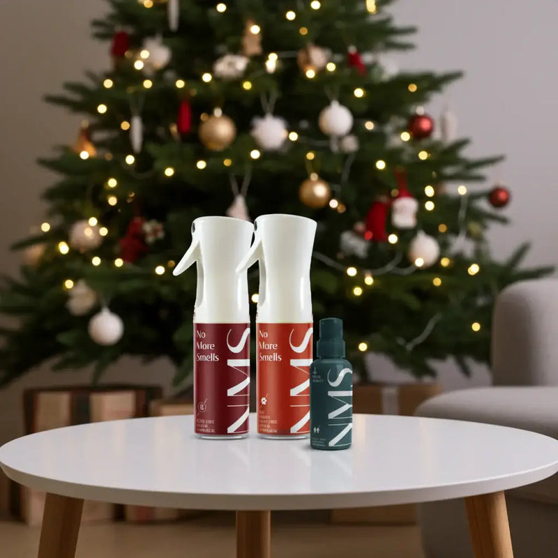 Three No More Smells spray bottles on a table with a decorated Christmas tree in the background